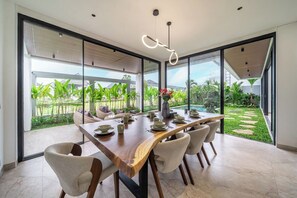 Ein Essbereich mit Holztisch, Stühlen und Blick auf Garten und Pool.