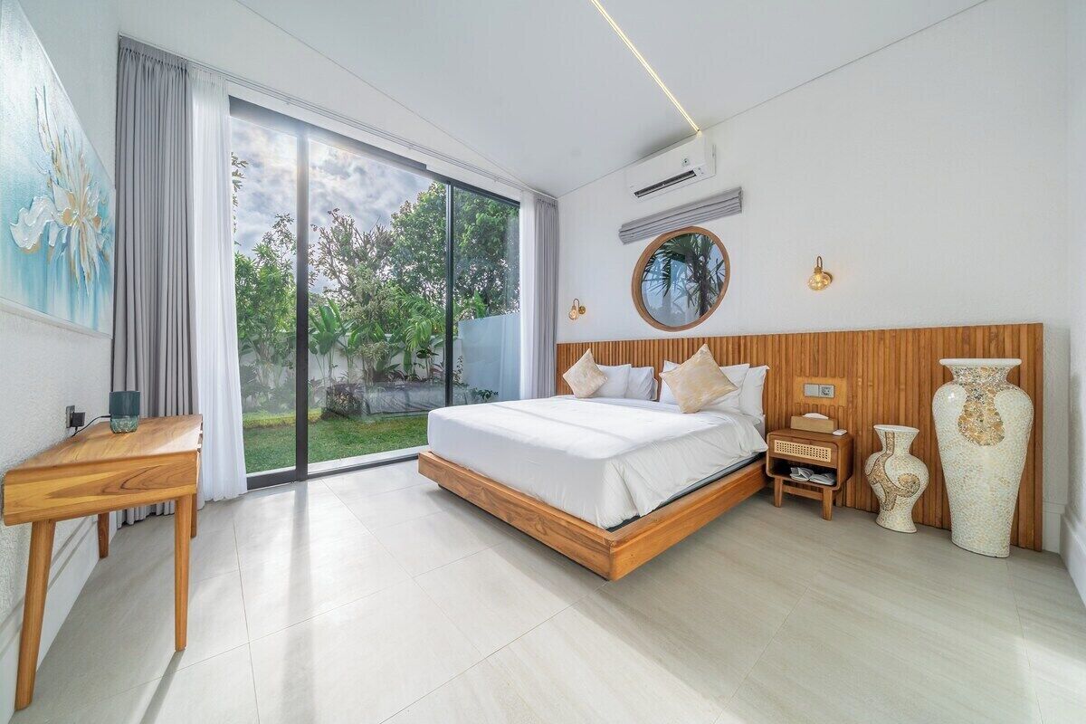 Ein modernes Schlafzimmer mit einem großen Bett, einem Holz-Kopfstück, einem Nachttisch und einer großen Vase.