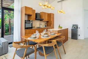 Une cuisine moderne avec des meubles en bois, une table à manger pour six personnes et une machine à café.