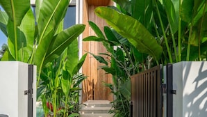 A modern house with a wooden door and a concrete pathway leading to the entrance. - ART1 - Designer Villa with 2 Bedrooms & Pool, Ubud (Gianyar Regency)