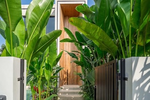 A modern house with a wooden door and a concrete pathway leading to the entrance. - ART1 - Designer Villa with 2 Bedrooms & Pool, Ubud (Gianyar Regency)