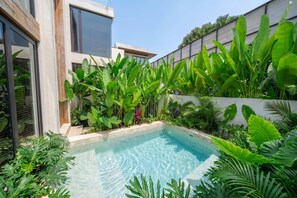 A modern pool with clear water, surrounded by lush tropical plants and a contemporary building with large windows. - ART1 - Designer Villa with 2 Bedrooms & Pool, Ubud (Gianyar Regency)