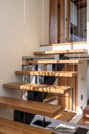A modern interior with a staircase made of wood and metal, leading to a room with a bed and a window. - ART1 - Designer Villa with 2 Bedrooms & Pool, Ubud (Gianyar Regency)