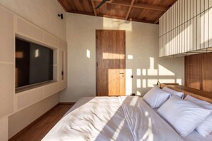 A bedroom with a large bed, a wooden door, and a window. - ART1 - Designer Villa with 2 Bedrooms & Pool, Ubud (Gianyar Regency)