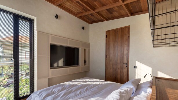 A bedroom with a large bed, a TV mounted on the wall, and a sliding door. - ART1 - Designer Villa with 2 Bedrooms & Pool, Ubud (Gianyar Regency)