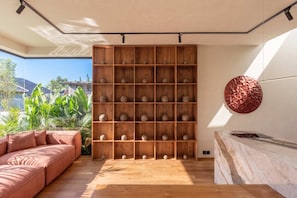 Una sala moderna con una estantería de madera, un adorno de cobre redondo en la pared y una encimera de mármol.