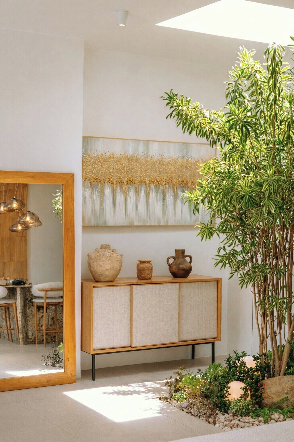 Un intérieur moderne avec un meuble en bois, une grande plante et une œuvre d’art murale.