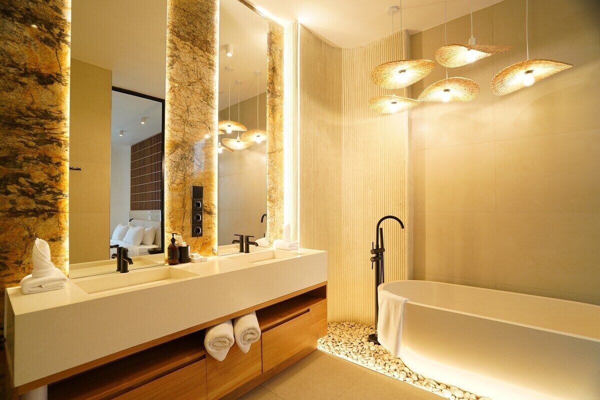 A modern bathroom with a large mirror, a white bathtub, and a wooden vanity.