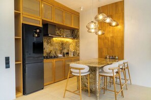 Eine moderne Küche mit einem schwarzen Kühlschrank, Holzschränken, einer Marmorarbeitsplatte und einer Bar mit Hockern.