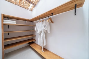 A modern bathroom with wooden shelves, a robe hanging on a rack, and a skylight. - Tropical 2BR in Serene Ubud w Pool & Huge Garden (Ubud)