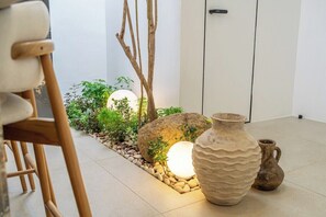 Une pièce comprenant un coin salon, une composition florale décorative, un grand vase et une porte.