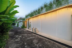 A pathway leading to a building with a flat roof, a planter with plants, and a wall with a light strip. - Designer 2BR in Ungasan w Pool & Beach Access (Badung Regency)