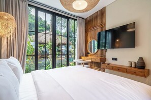 Ein modernes Schlafzimmer mit einem großen Bett, einem an der Wand montierten Fernseher und Blick ins Freie durch große Fenster.