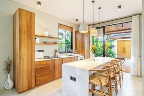 Eine moderne Küche mit Holzschränken, einer Kochinsel und Barhocker.