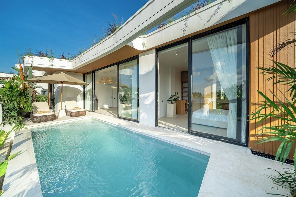 Une maison moderne dotée d’une piscine, de portes-fenêtres coulissantes et d’un espace salon extérieur.