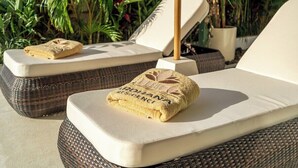 Dos sillones de descanso con toallas, uno con el texto 'ARDHANA RESIDENCE' y una planta en maceta al fondo.