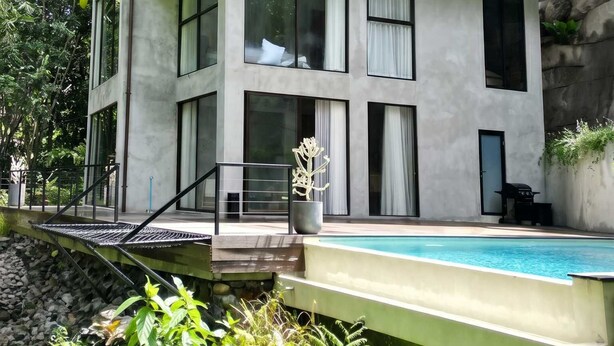 A two-story building with a balcony, large windows, and a swimming pool. - Jungle Villa, Brand New, Unique Art Design, Pool (Gianyar Regency)