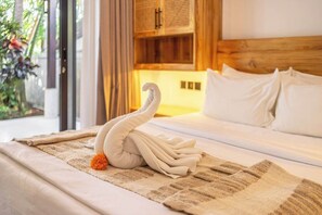 A neatly made bed with a swan-shaped towel and a small orange flower on a textured blanket. - Huge Tropical 3BR in Serene Ubud w Pool & Lounge (Ubud)