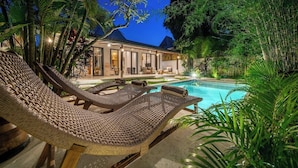 Ein Poolbereich mit Liegestühlen und einem Haus im Hintergrund.