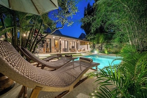 A poolside area with lounge chairs and a house in the background. - Huge Tropical 3BR in Serene Ubud w Pool & Lounge (Ubud)