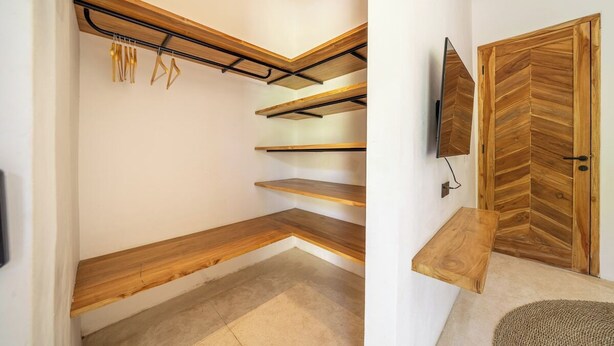 Ein modernes Interieur mit Holzbögen, einer Zargentür mit Fischgrätmuster und einem an der Wand befestigten Fernseher.