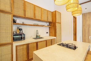 A kitchen with wooden cabinets, a microwave, a sink, and a gas stove. - Huge Tropical 3BR in Serene Ubud w Pool & Lounge (Ubud)