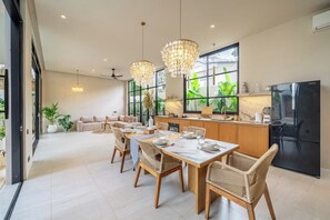Eine moderne Küche mit Essbereich, großen Fenstern und einem schwarzen Kühlschrank.