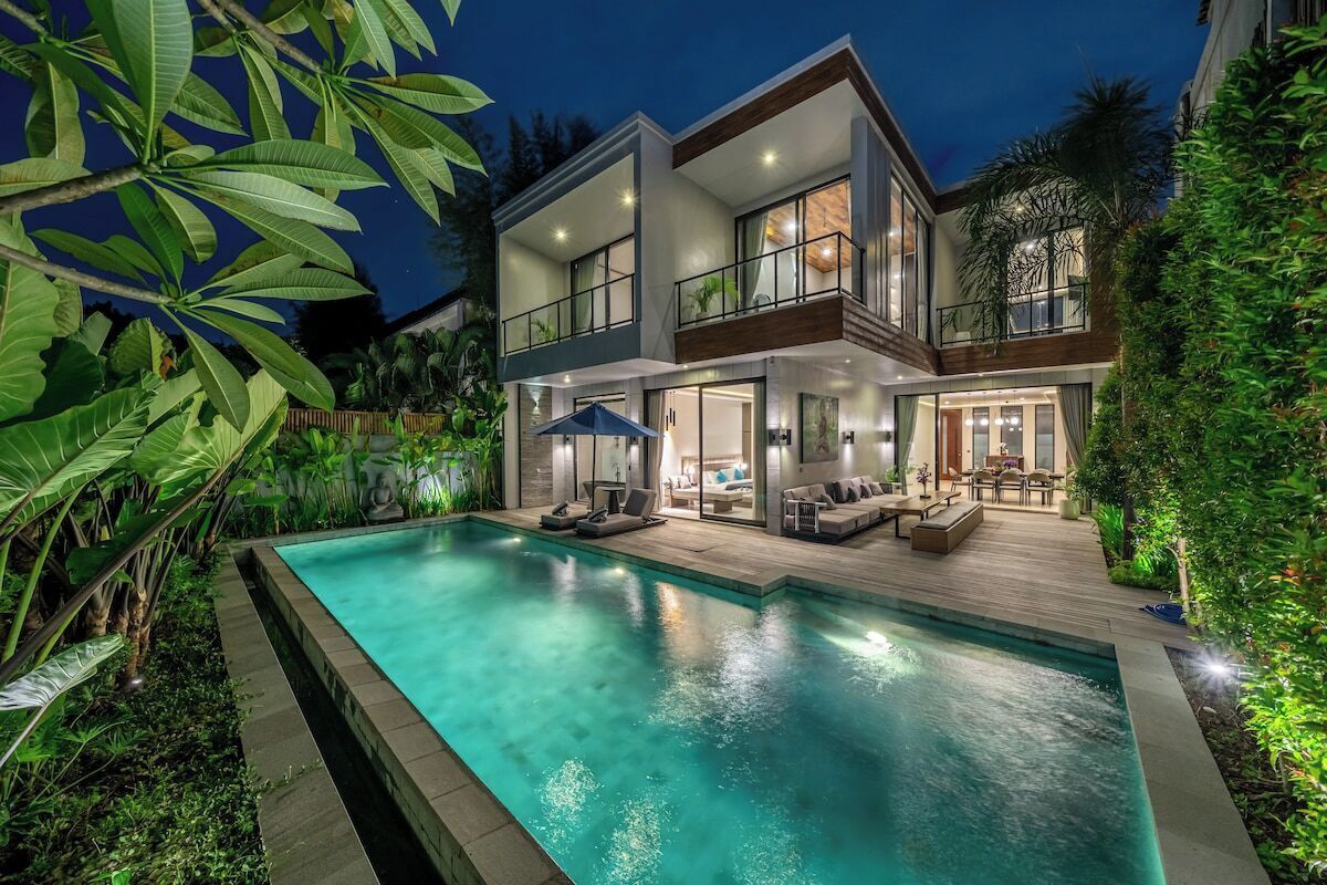 A modern two-story house with a swimming pool, outdoor seating, and lush greenery.