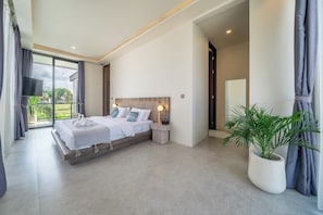 Ein modernes Schlafzimmer mit einem großen Bett, einem Nachttisch, einem Fernseher und einer Topfpflanze.