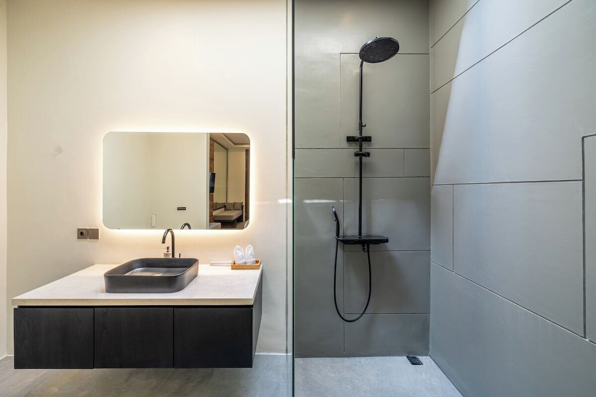 Un baño moderno con un espejo grande, un lavamanos y una ducha.