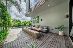 A modern outdoor deck with a wooden floor, a sofa, and a bench. - Chic 4BR Villa w/ Private Massage Room & Huge Pool (Badung Regency)