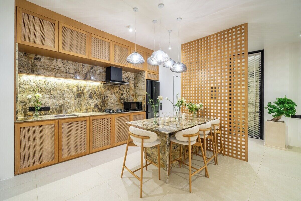 Een moderne keuken met een marmeren aanrechtblad, houten kastjes en een eethoek met een glazen tafel en barstoelen.