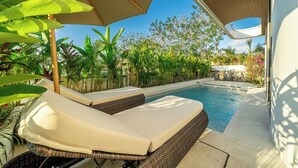 A poolside area with lounge chairs and a swimming pool, surrounded by lush greenery. - New Tropical 3BR Villa+Private Pool+Best Location (South Kuta)