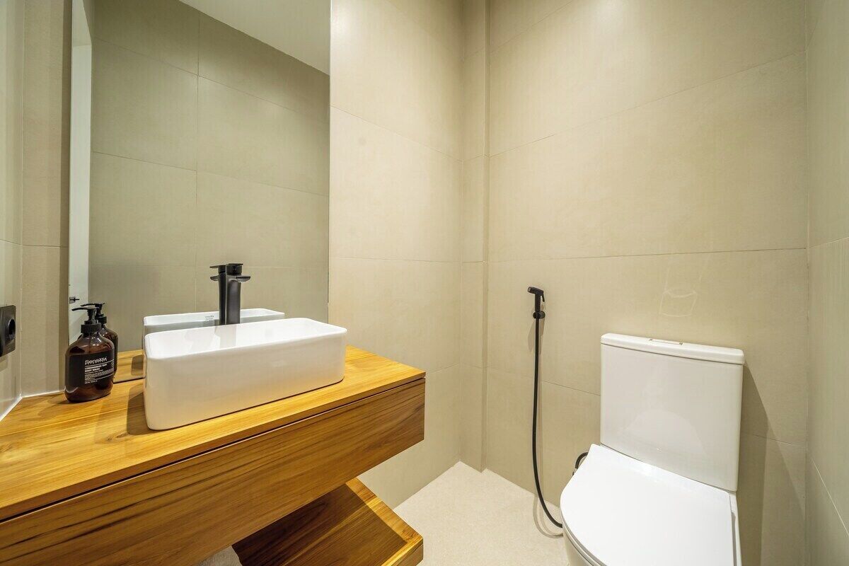 Ein Badezimmer mit einem weißen Waschbecken, einer Holzausstattung und einer Toilette.