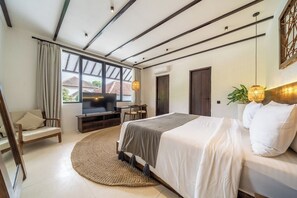 A modern bedroom with a large bed, a TV, a seating area, and a view of the outside. - Designer 3BR Stay in Ubud • Pool • Patio • Garden (Gianyar Regency)