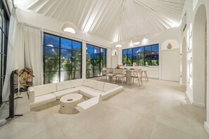 A spacious living area with a large sectional sofa, a round coffee table, and a dining area with chairs and a table. - Luxe 3BR Villa • Beach Nearby • Pool • Prime Spot (Badung Regency)