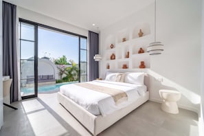 Quarto moderno com uma cama grande, vista para uma piscina e uma coleção de cerâmica na parede.