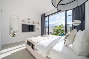 A modern bedroom with a large bed, a television, a mirror, and a view of the outdoors. - Luxe 3BR Villa • Beach Nearby • Pool • Prime Spot (Badung Regency)