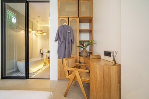 A modern bathroom with a freestanding bathtub, wooden furniture, and a glass shower enclosure. - Chic 2BR Villa in a Prime Location w Pool & Garden (Badung Regency)