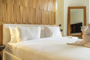 Une chambre d’hôtel avec une tête de lit en bois, un lit avec du linge de lit blanc, une table de chevet et un miroir.