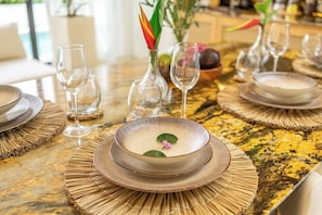 A dining table set with plates, bowls, and wine glasses, with a decorative centerpiece and a vase with a plant. - Chic 2BR Villa in a Prime Location w Pool & Garden (Badung Regency)