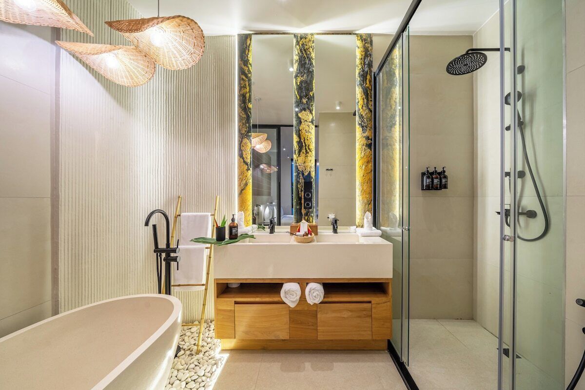 A modern bathroom with a freestanding bathtub, a glass-enclosed shower, and a vanity with a marble backsplash.
