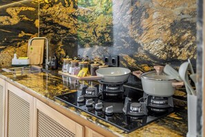 A kitchen with a granite countertop, a gas stove, and a pot on the stove. - Chic 2BR Villa in a Prime Location w Pool & Garden (Badung Regency)