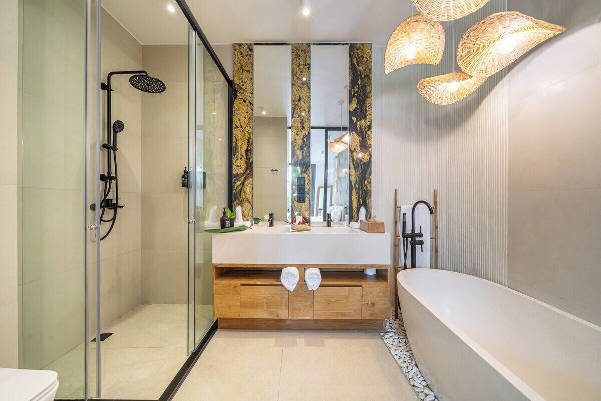 Een moderne badkamer met een glazen douchecabine, een houten wastafelmeubel en een vrijstaand bad.