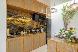 A kitchen with a marble backsplash, wooden cabinets, and a black refrigerator. - Chic 2BR Villa in a Prime Location w Pool & Garden (Badung Regency)