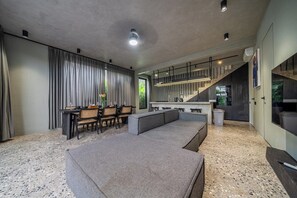 A modern interior with a seating area, kitchen, and staircase. - Predmet Padonan - Designer 3BR Villa w Pool, Rooftop Kitchen & Patio (Badung Regency)
