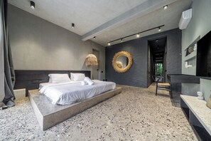 Un dormitorio moderno con una cama grande, un espejo redondo y suelo de hormigón.