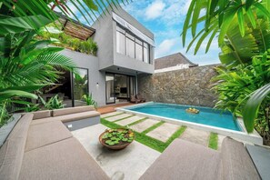 A modern house with a swimming pool, stone wall, and lush greenery. - Predmet Padonan - Designer 3BR Villa w Pool, Rooftop Kitchen & Patio (Badung Regency)