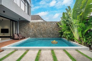 A modern house with a swimming pool, stone wall, and lush tropical plants. - Predmet Padonan - Designer 3BR Villa w Pool, Rooftop Kitchen & Patio (Badung Regency)