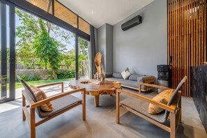 A modern living room with a round wooden coffee table, two sofas, and a television. - Jungle 9BR Ubud Paradise with spa! (Ubud)